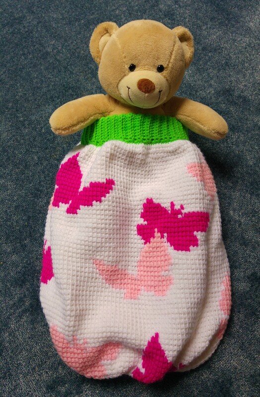 Weißer Babyschlafsack im Pixelhäkelmuster mit rosa und pinken Schmetterlingen und grünem Rippenbündchen