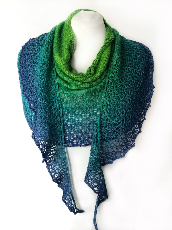 Green-to-navy gradient knitted crescent shawl with lace border on a white mannequin