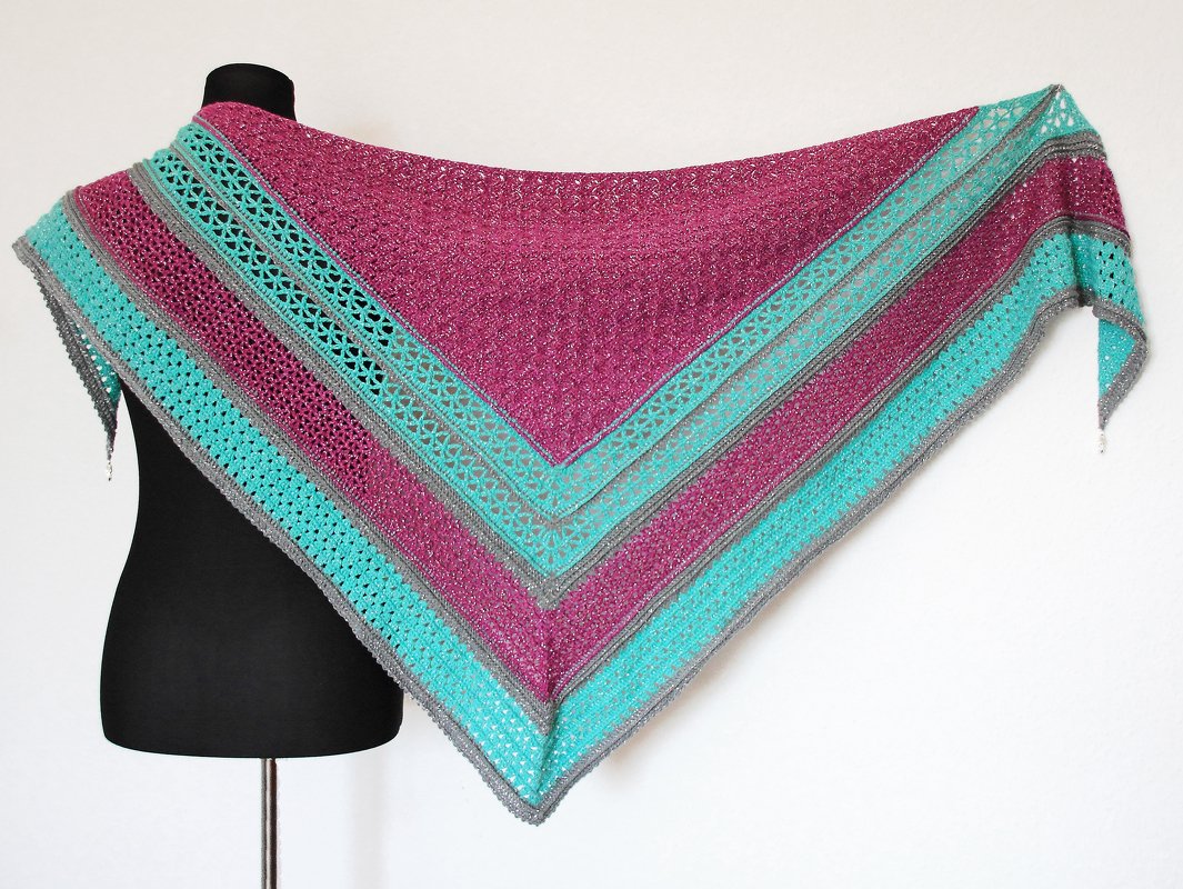 Gehäkeltes Dreieckstuch in Magenta, Türkis und Grau auf einer Schneiderpuppe drapiert, mit offenem Spitzenmuster.