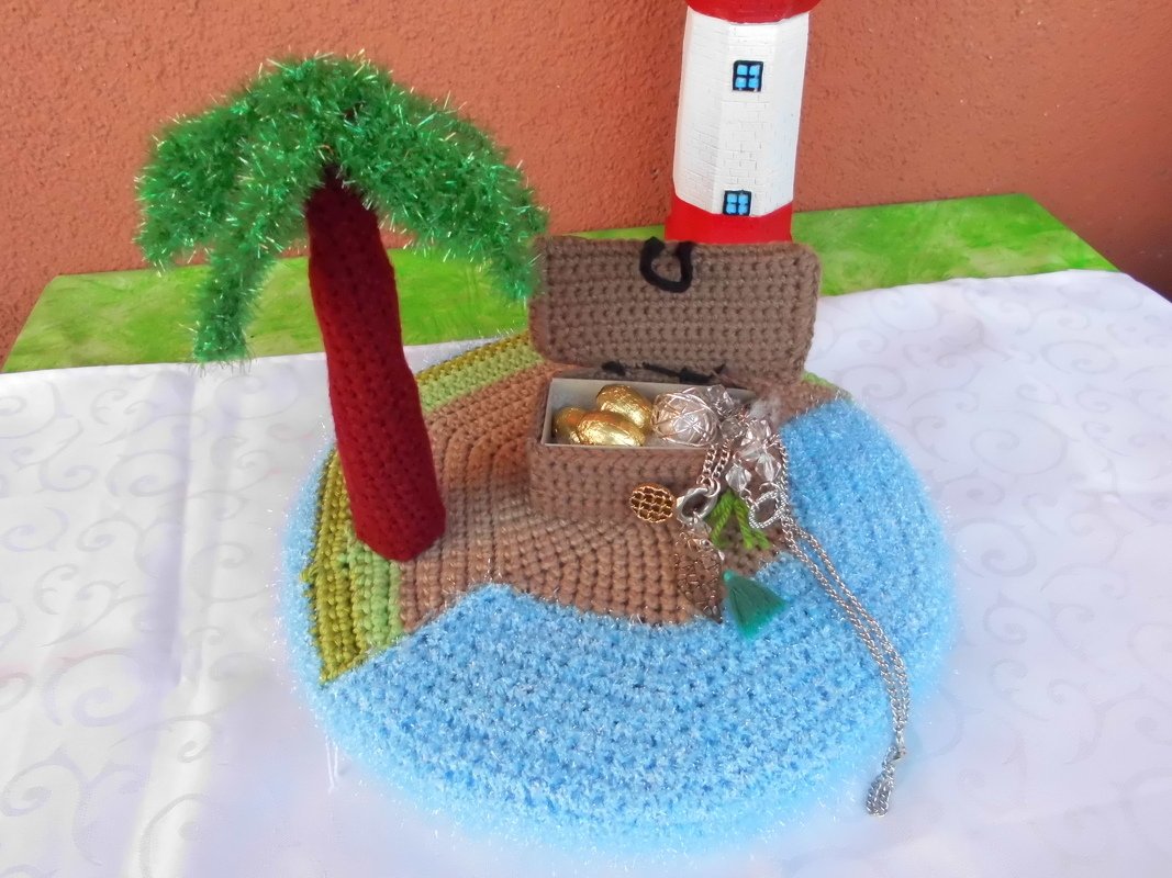 Gehäkelte Miniatur-Insel mit Palme, Leuchtturm und offener Schatzkiste mit Schmuck