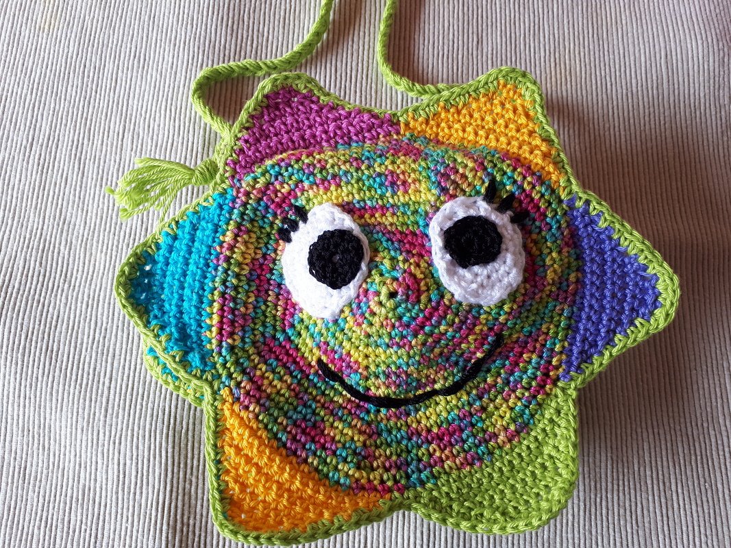 sternförmige gehäkelte Umhängetasche in bunten Farben mit aufgenähten Augen und grüner Einfassung