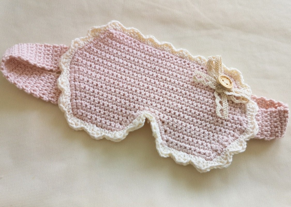 Gehäkelte Schlafmaske rosa mit weißer Rüsche, Schleife und Holzknopf