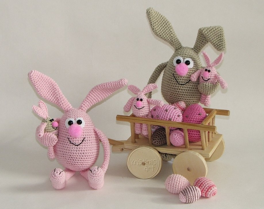 Amigurumi-Osterhasen in Rosa und Beige mit Holz-Bollerwagen, darin gehäkelte Ostereier und kleine Häschen.