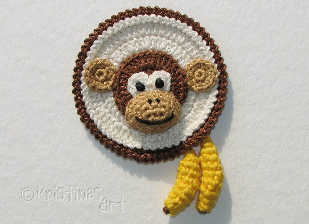 Runde Häkelapplikation mit Affengesicht und zwei kleinen Bananen