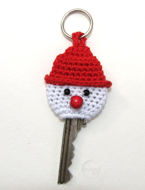 Schlüssel mit gehäkelter weißer Hülle, roter Mütze und Perlenaugen sowie roter Perlennase am Schlüsselring
