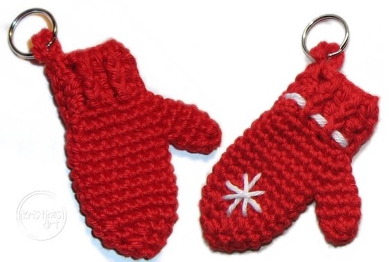Zwei gehäkelte rote Fäustlinge als Schlüsselanhänger mit Metallringen und weißen Stickstichen