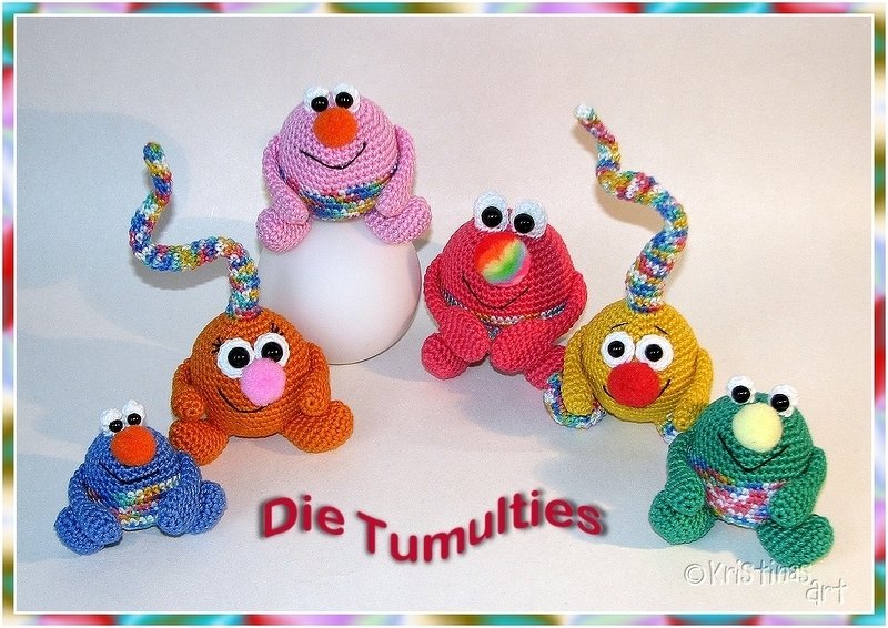 Sechs fröhlich wirkende, gehäkelte Amigurumi-Figuren in leuchtenden Farben, einige mit regenbogenfarbigen Fühlern, auf weißem Hintergrund.