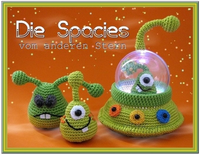 Drei gehäkelte grüne Amigurumi-Aliens und ein UFO mit beleuchtetem Alien vor orangefarbenem Sternenhimmel.