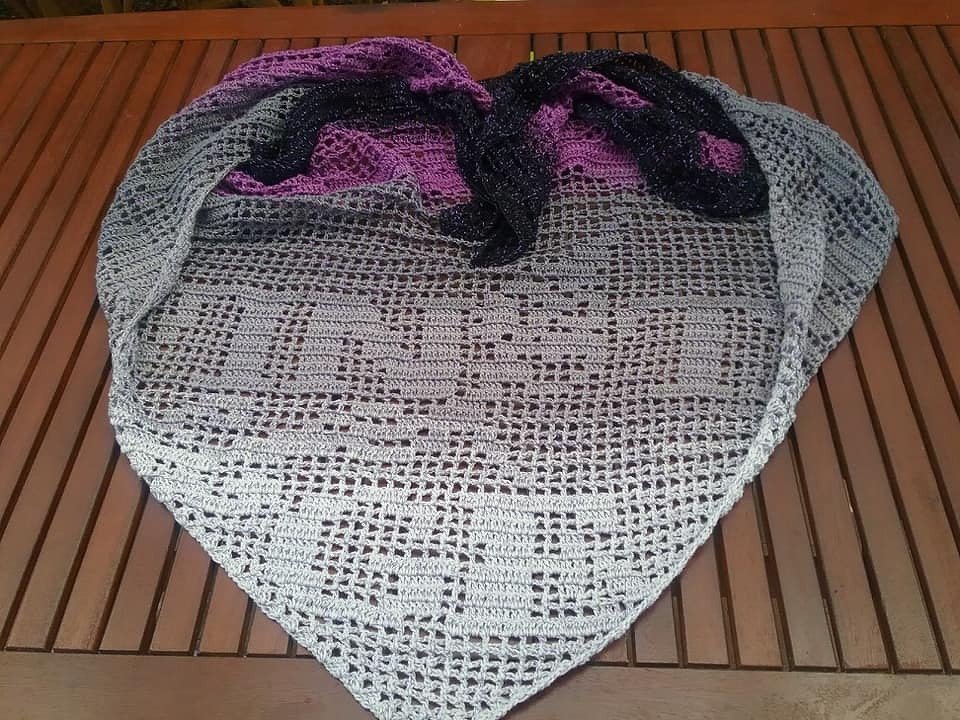 Dreieckstuch in Filettechnik mit eingearbeitetem Schriftmotiv, Grau-Lila-Schwarz, auf Holztisch ausgelegt
