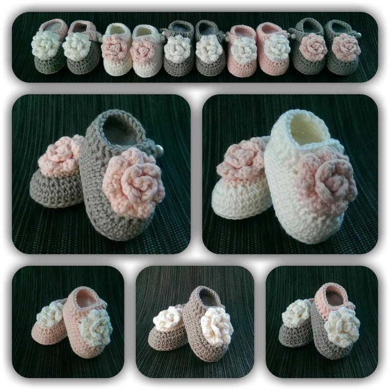 Eine Reihe gehäkelter Babyschuhe in Grau, Weiß und Rosa, verziert mit gehäkelten Blumen.
