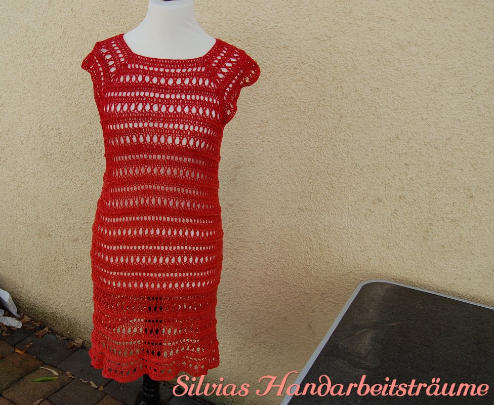 Rotes, kurzärmliges Häkelkleid mit Lochmuster auf weißer Schaufensterpuppe vor beiger Wand
