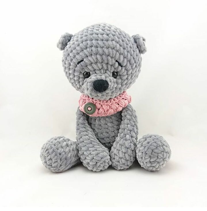 Gehäkelter grauer Amigurumi-Teddybär sitzend mit rosa Halskrause und Knopf