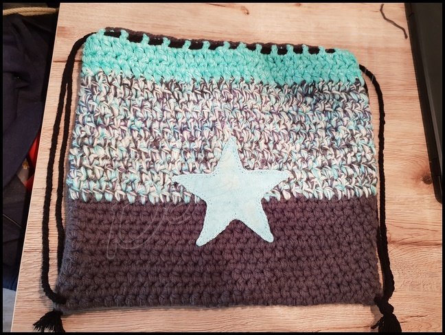 Rechteckiger gehäkelter Rucksack mit Kordelzug, klaren Farbblöcken und Stern-Applikation