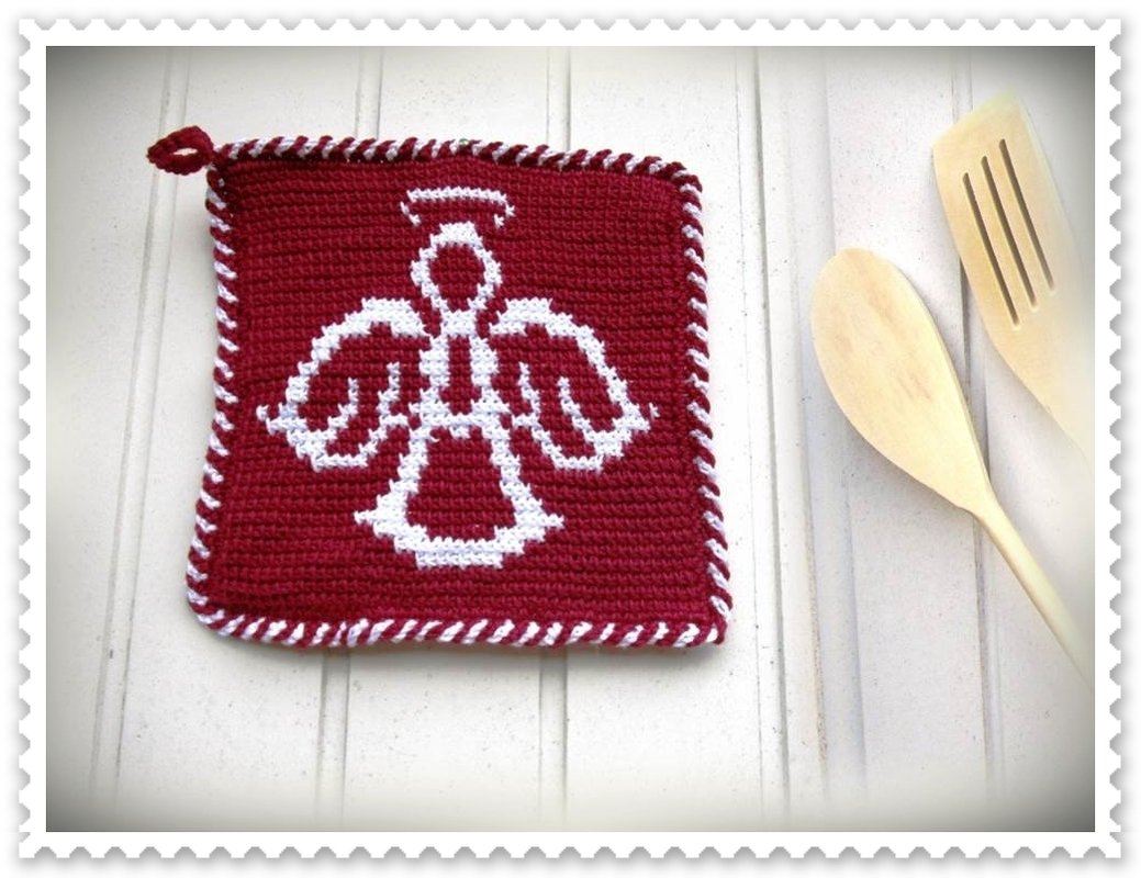 Roter gehäkelter Topflappen mit weißem Engelmotiv und weißem Kordelrand, daneben Holzlöffel und Holzpfannenwender