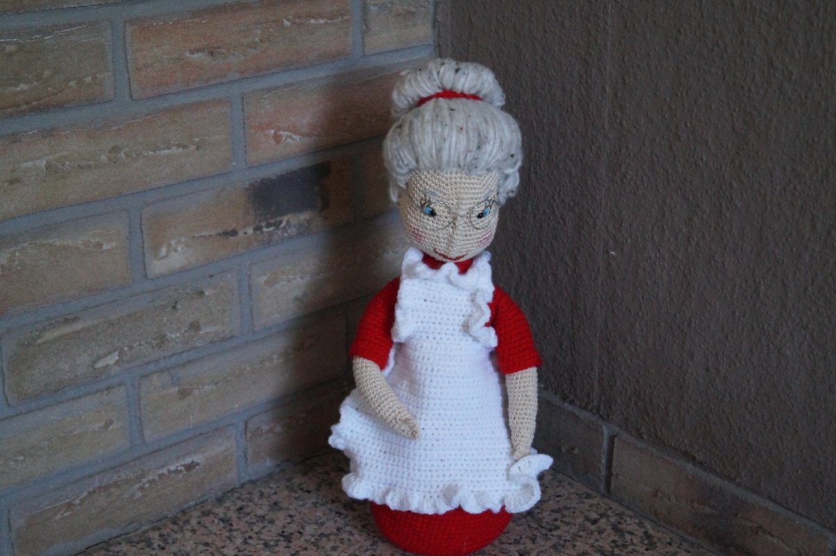 Gehäkelte Weihnachtsfrau in rotem Kleid, weißer Schürze und Brille