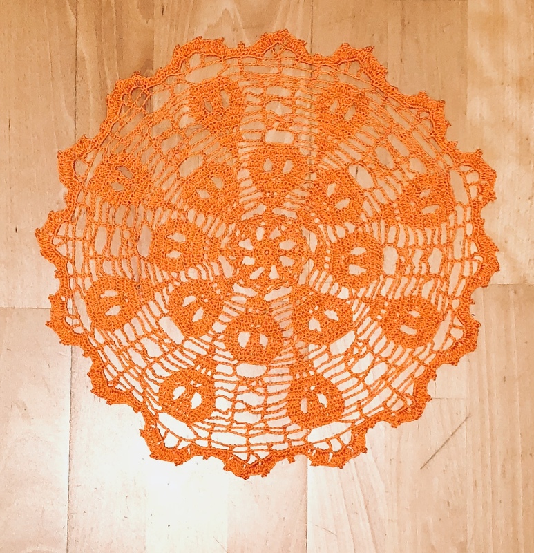 Rundes orangefarbenes gehäkeltes Deckchen mit Kürbissen