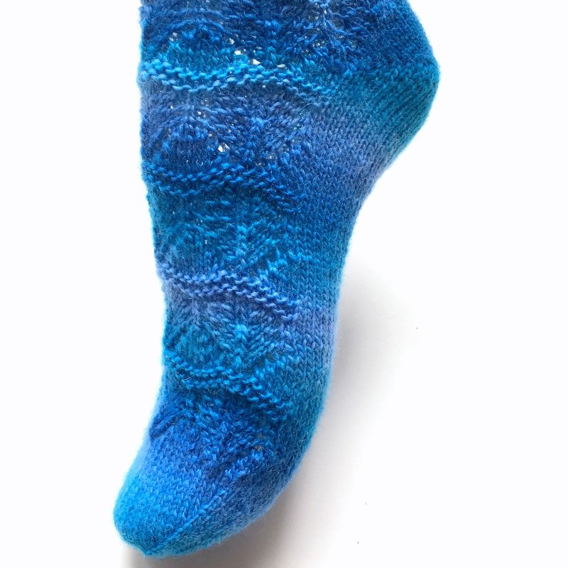 Blaue gestrickte Damensocke mit Lochmuster und Farbverlauf vor weißem Hintergrund