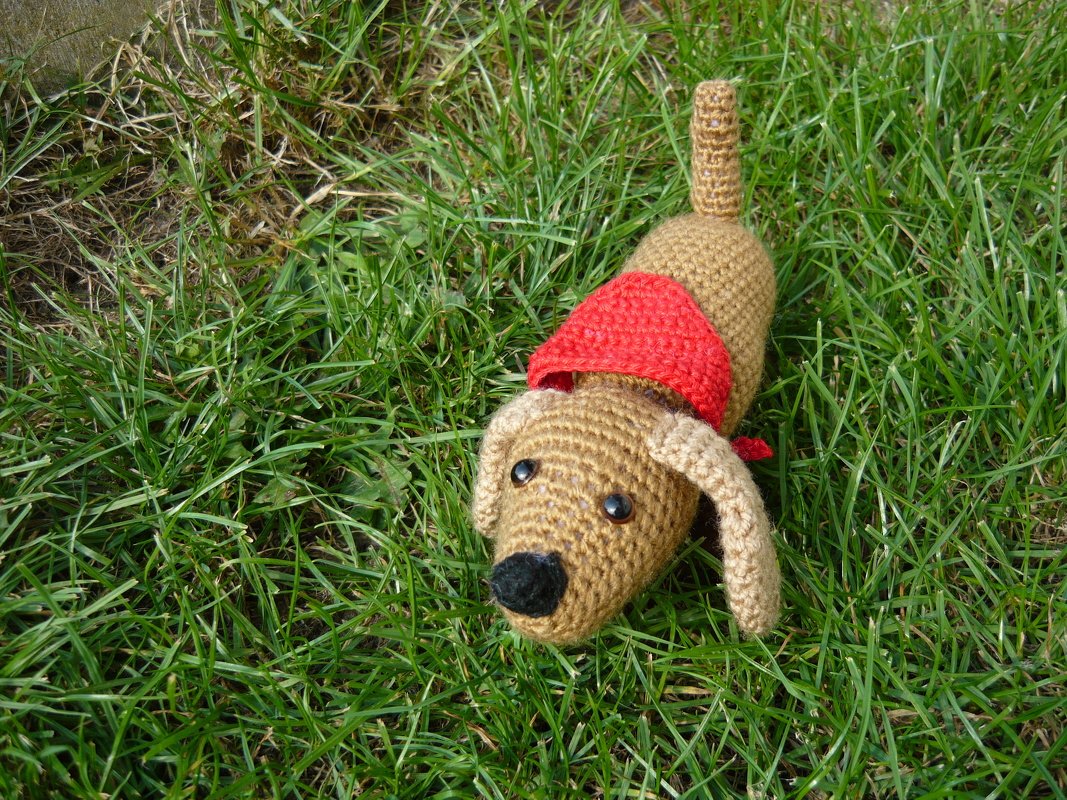 Gehäkelter Dackel in Braun mit rotem Halstuch auf Gras