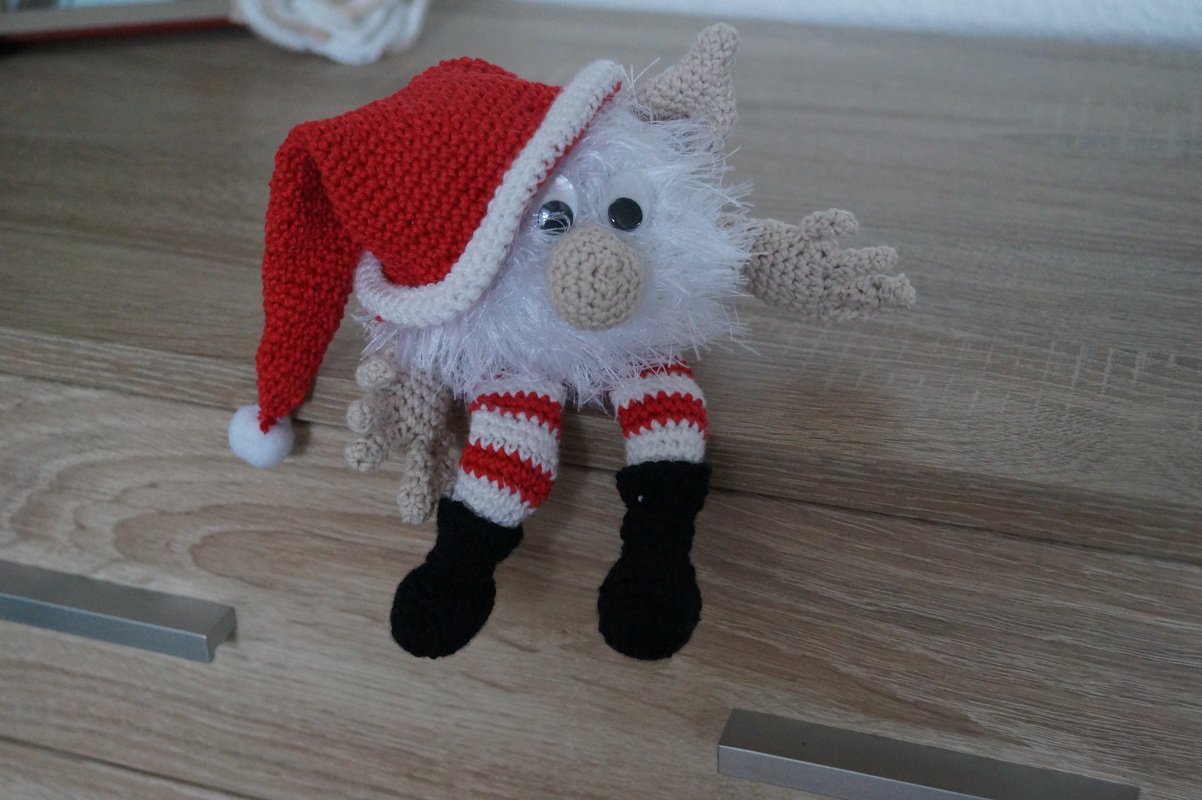 Gehäkelter Weihnachtswichtel mit roter Zipfelmütze, flauschigem Bart und gestreiften Beinen