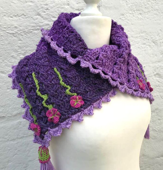 Lila gehäkelter Loopschal mit grünen Ranken, pinken Blumen und Quaste