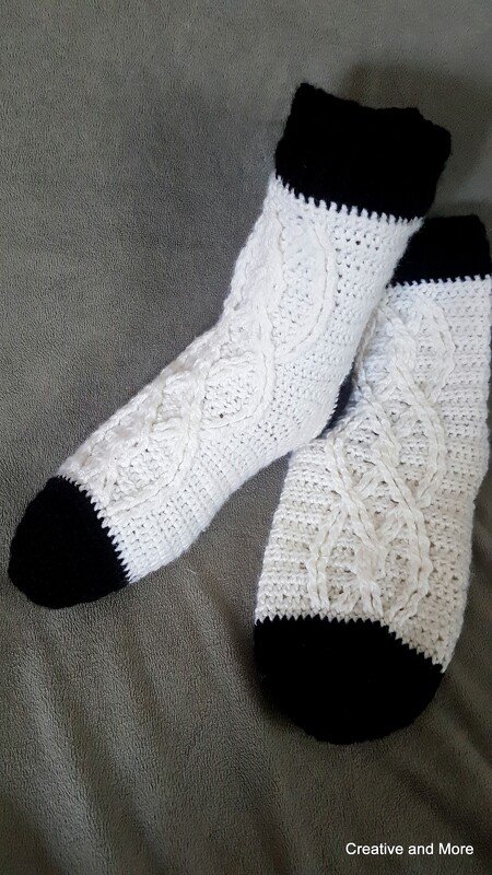 Weiße gehäkelte Socken mit schwarzem Bündchen und schwarzer Spitze, Zopfmuster