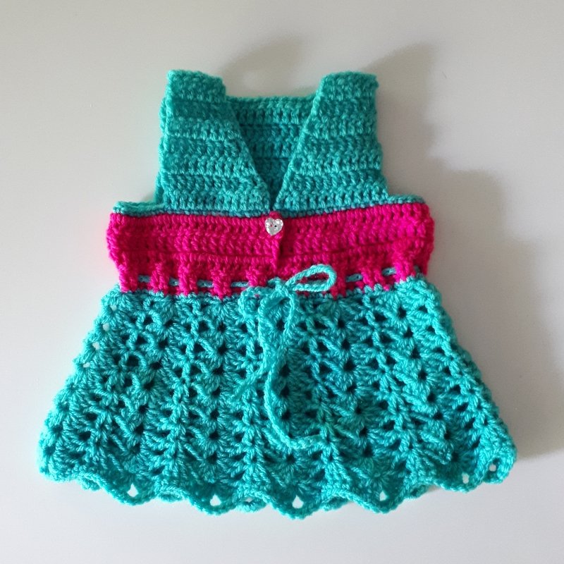 Gehäkeltes Babykleid in Türkis und Pink mit V-Ausschnitt, Herzknopf und Muschelmuster am Rock
