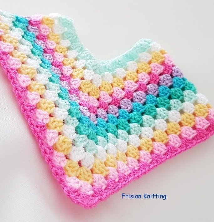 Pastel granny square crochet poncho with a V-neckline, rows of pink, yellow, mint, teal, and white, edged in bright pink.