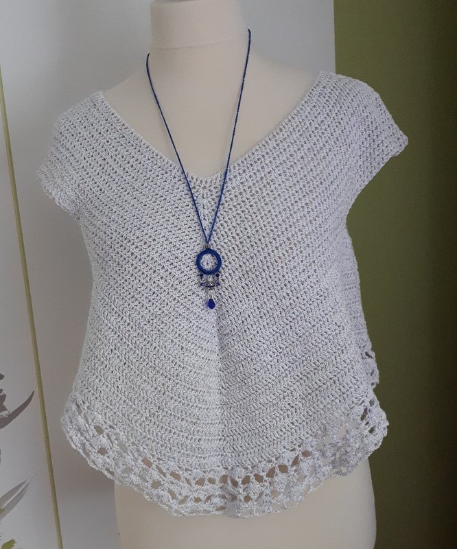 Hellgraues gehäkeltes Damen-Top auf Schneiderpuppe mit blauer Halskette