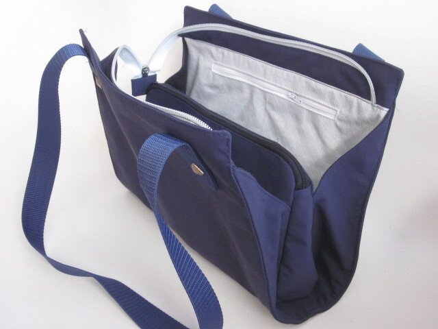 Marineblaue Umhängetasche mit geöffnetem Hauptfach, Reißverschlüssen und verstellbarem Schultergurt