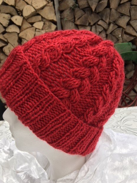 Details einer roten grob gestrickten Beanie mit Zopfmuster und umgeschlagenem Rand