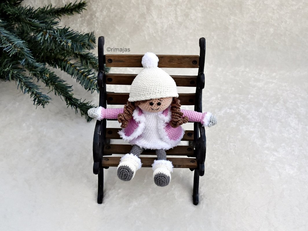 Gehäkelte Amigurumi-Puppe mit Bommelmütze auf Holzbank
