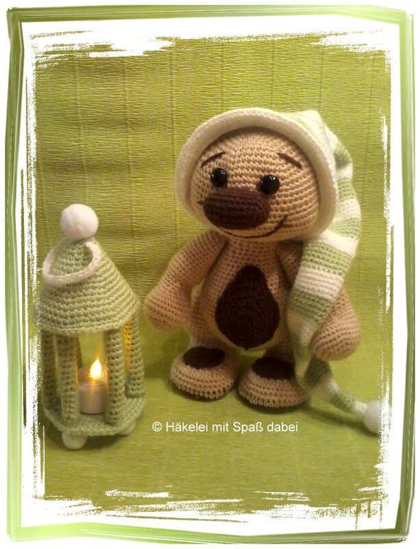 Gehäkelter Amigurumi-Teddybär mit gestreifter Schlafmütze neben gehäkelter Laterne
