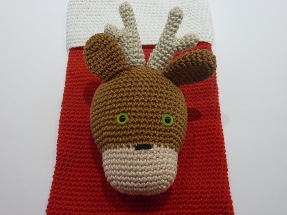 Gehäkelter brauner Rentierkopf mit beigem Maul und Geweih auf rotem Weihnachtsstrumpf