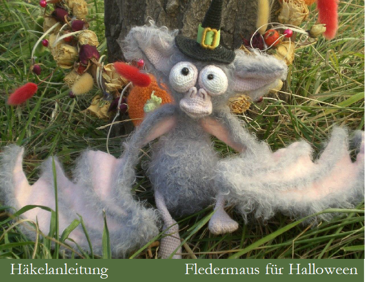 Gehäkelte graue Fledermaus-Amigurumi mit Hexenhut und großen Augen im Gras