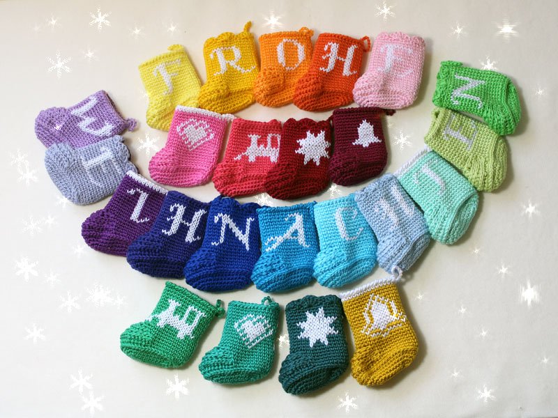 Bunte gehäkelte Weihnachtssöckchen mit Buchstaben und Motiven in Reihen