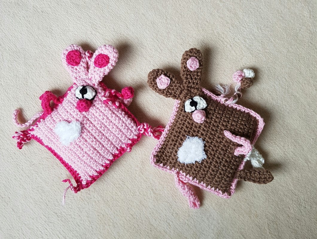 Zwei gehäkelte Schnuffeltücher in Rosa und Braun mit Hasenohren, flauschigem Bauchfleck und Augen auf hellem Untergrund