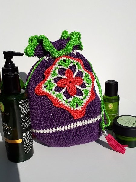 Gehäkelter Kordelzug-Beutel mit Granny-Flower-Applikation, Rüschenkante und Quaste