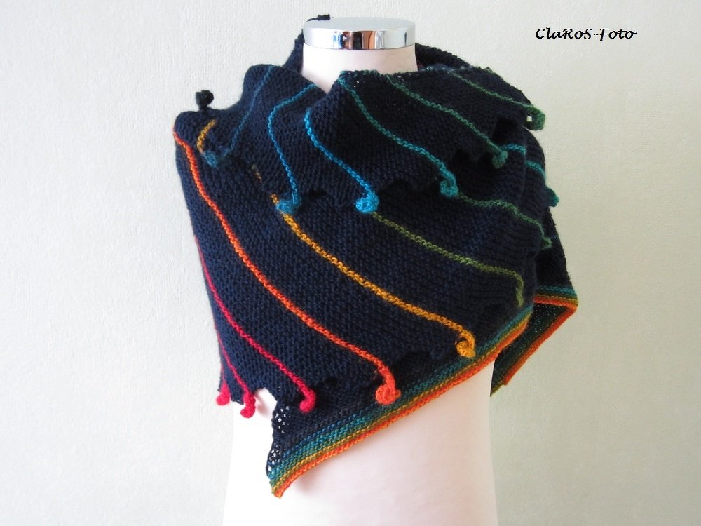 Navy knitted triangle shawl on a mannequin with diagonal rainbow-colored stripes and small bobble accents