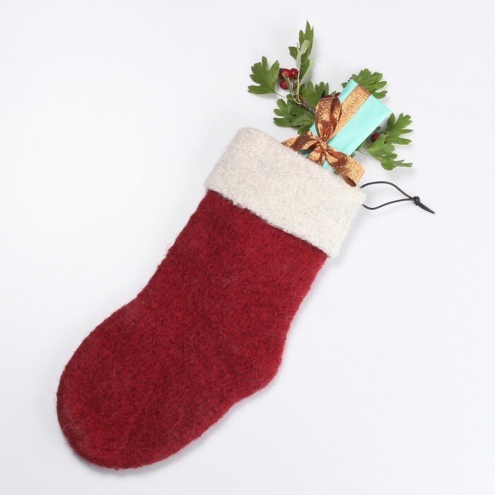 Red hand-felted Christmas stocking with white cuff holding a teal gift and greenery