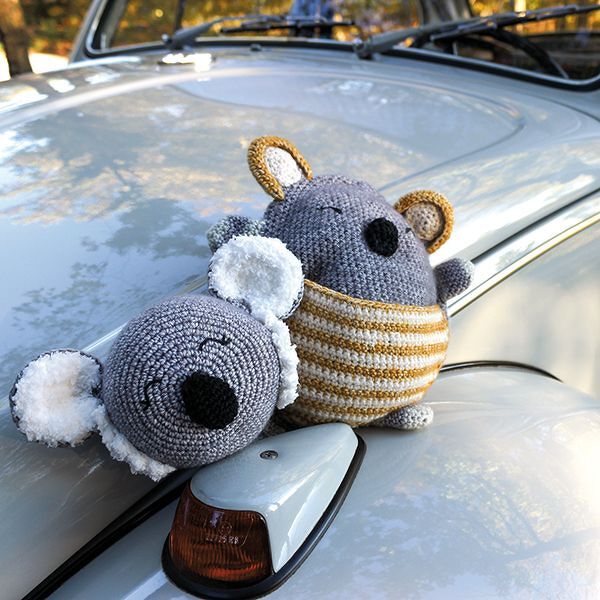 Zwei gehäkelte Amigurumi-Koalas, einer mit gelb-weißem Ringelbauch und flauschigen Ohren, auf einer Autohaube.