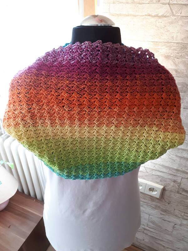 Gehäkelter Loop-Schal in mehrfarbigem Verlauf von Violett über Orange, Gelb zu Grün und Türkis auf einem Mannequin.