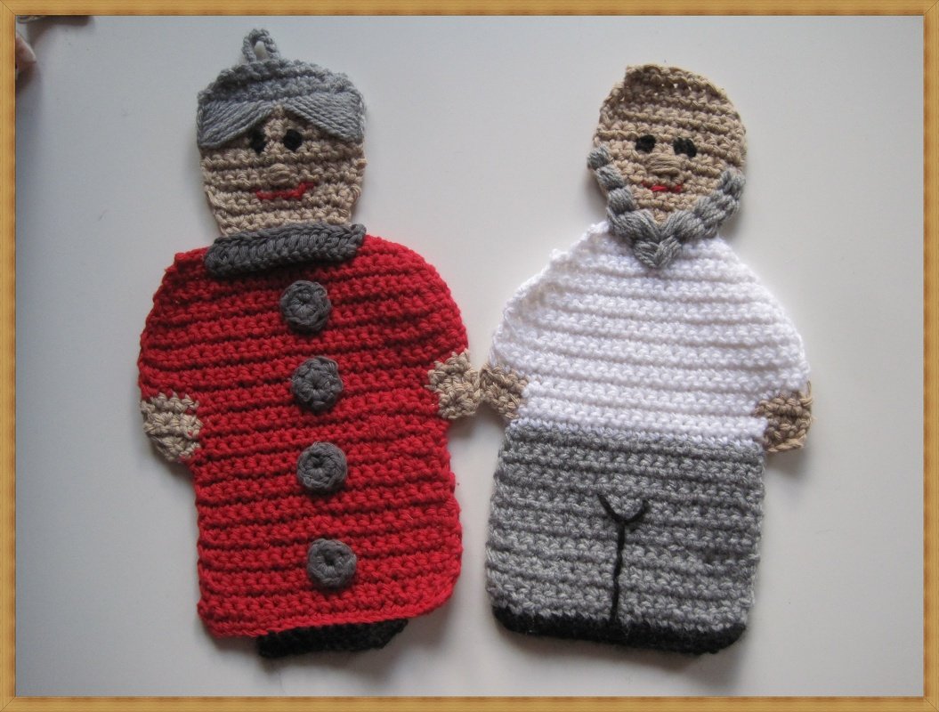 Zwei gehäkelte Topflappen in Figurenform: links rot mit grauer Kopfbedeckung, rechts weißes Oberteil und graue Hose mit Bart.