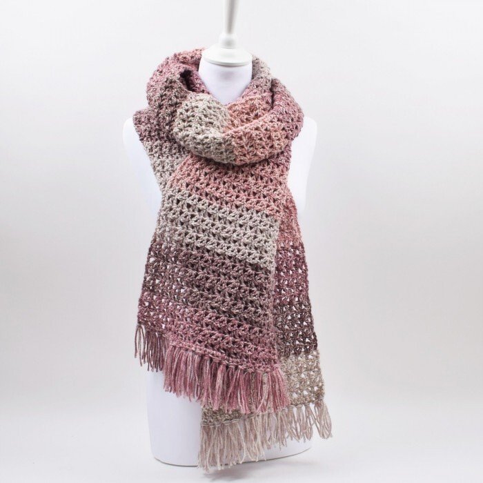 Ombre crochet scarf in pink, mauve, and beige with fringe on a mannequin.