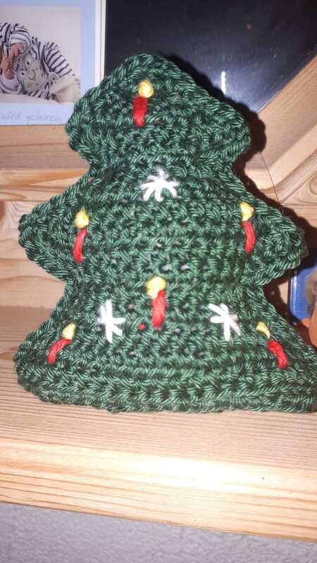 Kompakter schnell gehäkelter Weihnachtsbaum in Dunkelgrün mit roten, gelben und weißen Stickakzenten