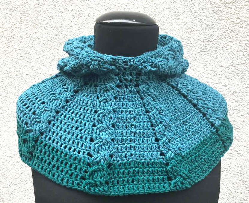 Türkisfarbene gehäkelte Poncholette mit rüschigem Kragen auf schwarzer Schneiderpuppe