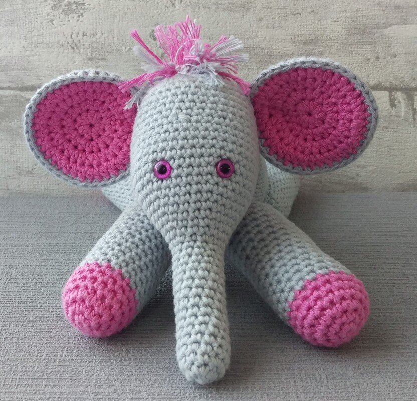 Grey and pink crocheted amigurumi elephant with pink inner ears and feet.