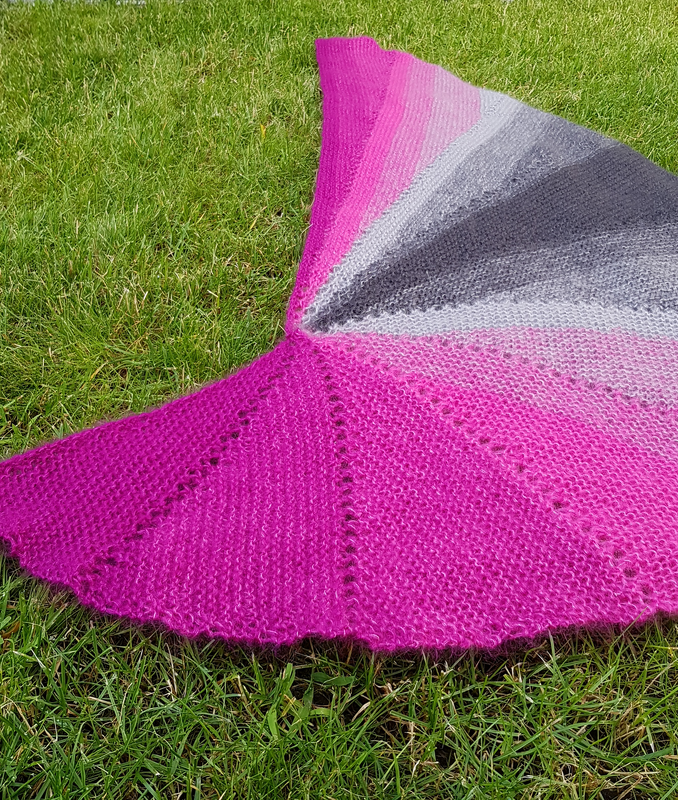 Halbrundes Stricktuch Magenta-Grau mit Lochmuster auf Gras