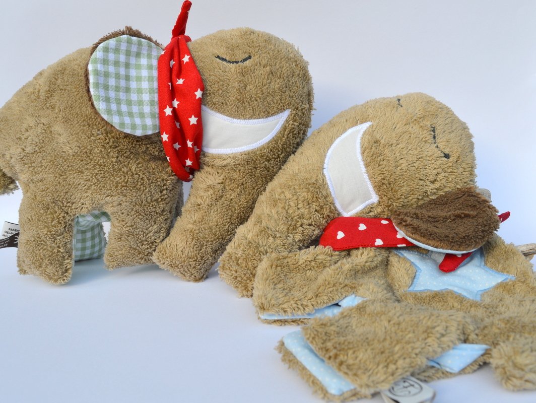 Nahaufnahme von Elefanten-Kuscheltieren mit applizierten Gesichtern, kontrastierenden Ohrenstoffen und roten Halstüchern.