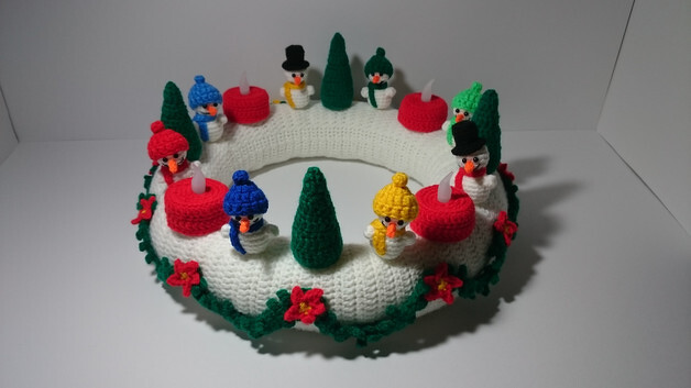 Runder weißer gehäkelter Adventskranz mit Schneemann-Figuren, grünen Tannen und roten Kerzen