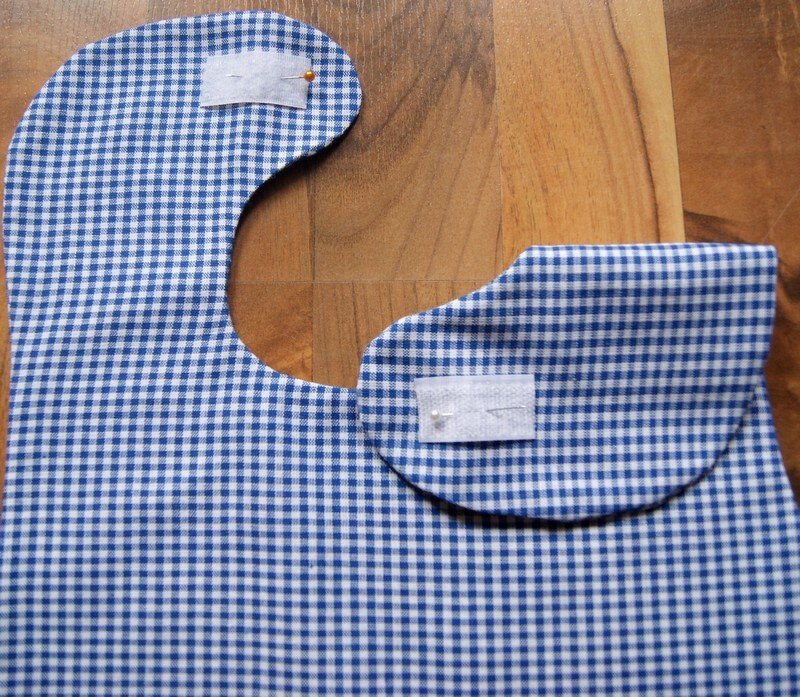 Zwei Babylätzchen-Schnittteile aus blau-weiß kariertem Stoff mit angeheftetem Klettverschluss